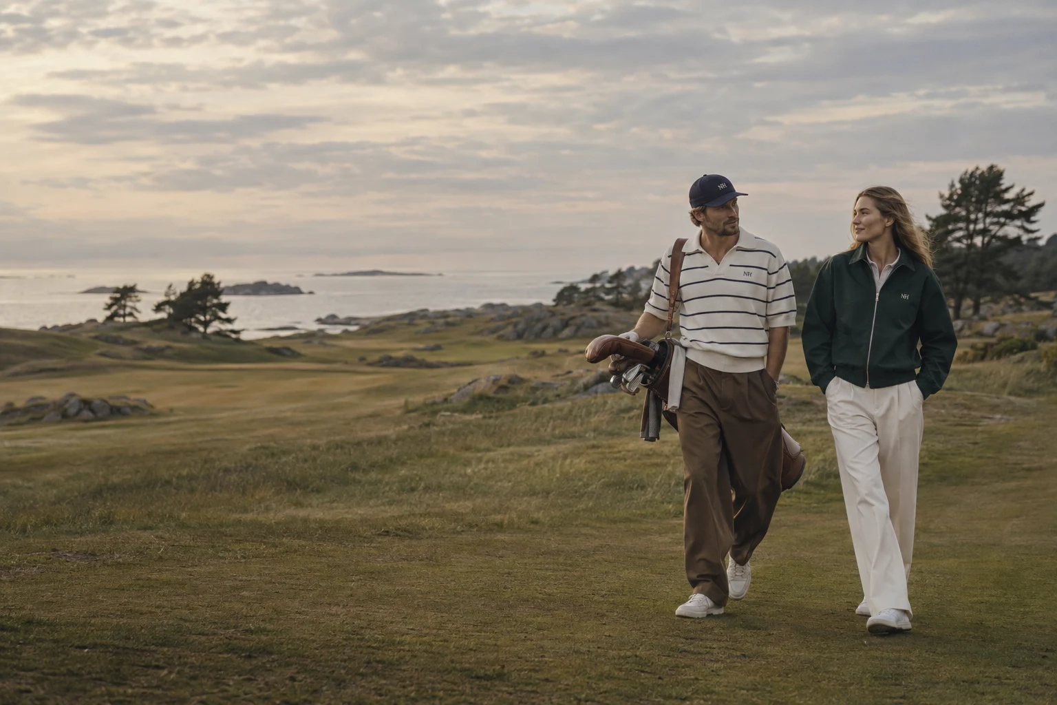 Two friends walking a coastal fairway in the Norr Hours collection